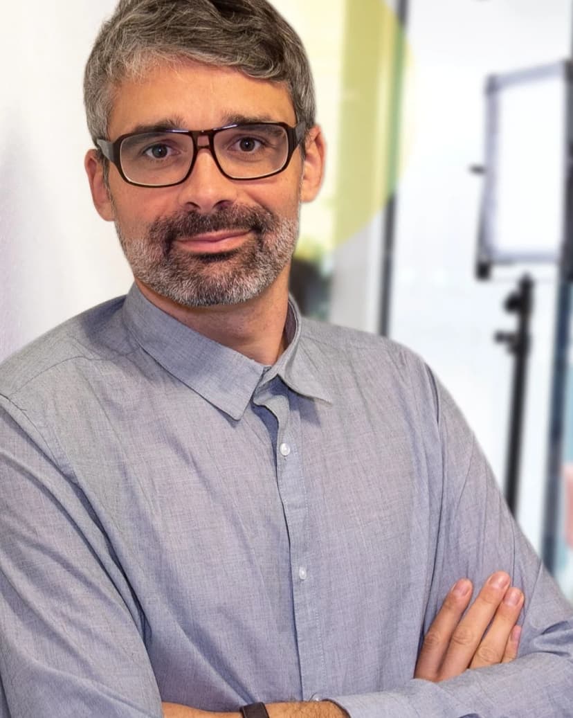 Portrait Tobias Büchner mit kurzem Haar und Bart, einer Brille mit dunklem Rand und einem hellgrauen Hemd.