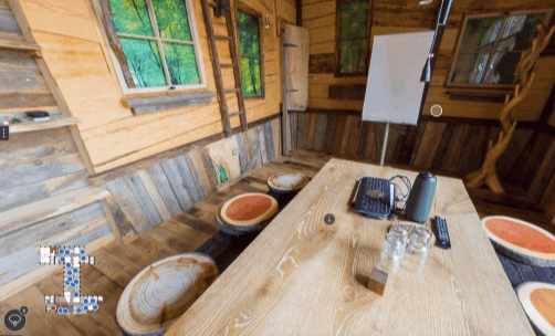 Blick in ein rustikal eingerichtetes Holzhaus mit Sitzecke und Fenster.