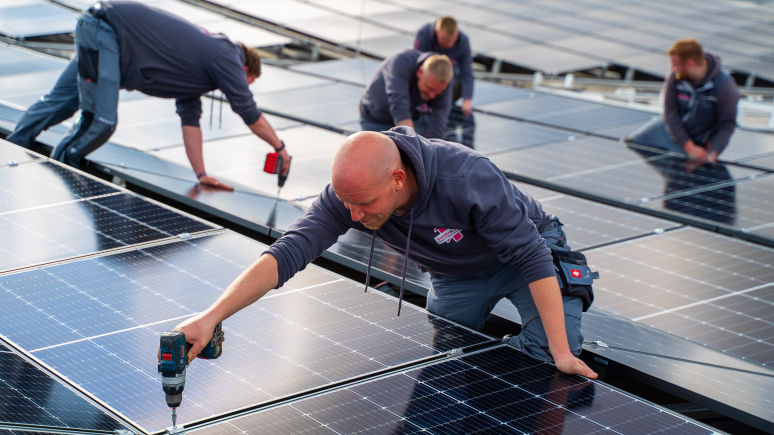 Ein Elektroinstallateur montiert eine Photovoltaikanlage.